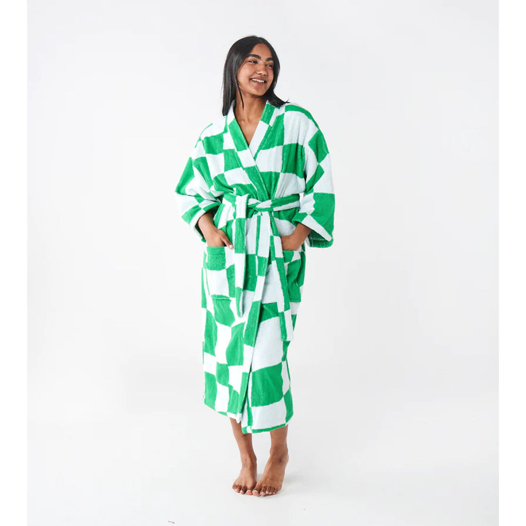 woman with dark skin and black hair models a green and white checkerboard terry towel dressing gown